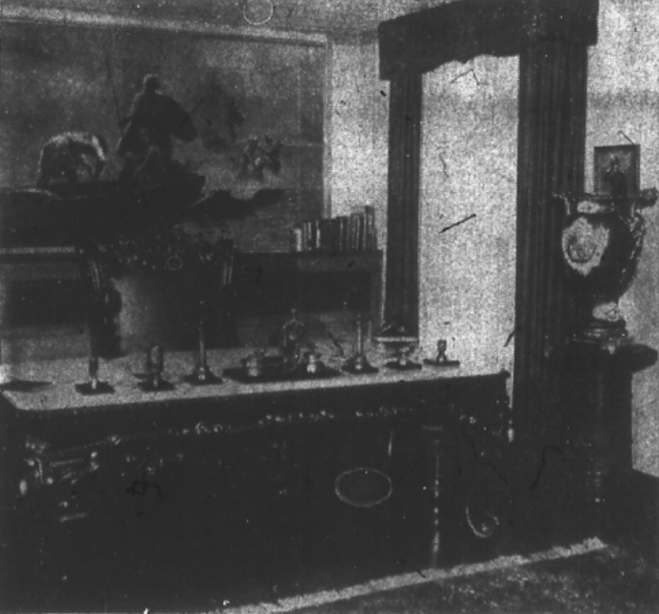 Newspaper image: In the "study" portion of the room is this huge rosewood desk trimmed with gold leaf, as is the mahogany chair. The bronze desk set is from Mr. Lefkowsky's home in Russia. The painting, "Gauls Feeling from Caesar," is by E. Haussler; and the large vase on the pedestal is one of a pair of Se'vres porcelain, decorated with medallions, with massive bronze base and handles. Made in Se'vres, France in 1810, the vases are from the collection of Monsieur A. Petrone, Paris.